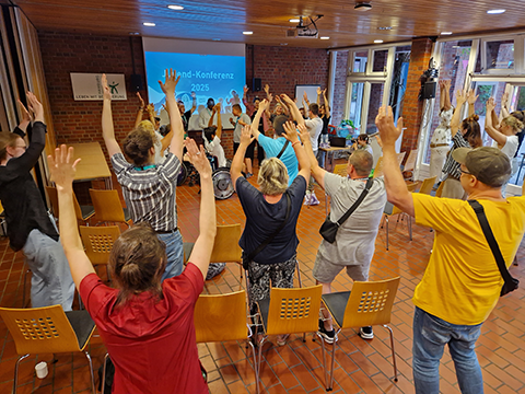 Teilnehmer*innen der Jugendkonferenz tanzen und recken dabei die Hände in die Höhe